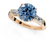 3 Stone Engagement Ring Setting for Fancy Blue Round Cut Center with Tapered Baguettes, Plain Band and Prong Head in Rose Gold