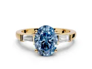 3 Stone Engagement Ring Setting for Fancy Blue Oval Center with Channel Baguette Accents and Prong Head in Yellow Gold